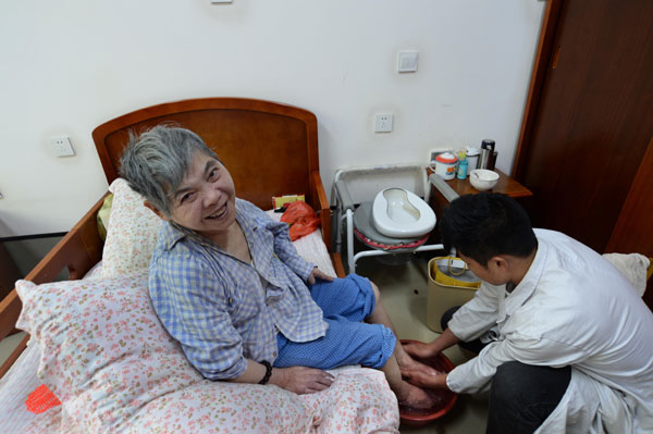 A man from a social welfare center for the aged in Guiyang, Guizhou province, washes the feet of 87-year-old Cai Sifen. China is in great need of nursing home beds and professional caretakers for the elderly. [Photo by Qiao Qiming/For China Daily]