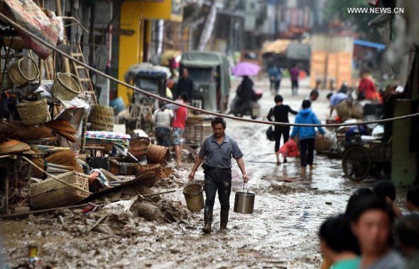 A man walks on a muddy road after a flood withdrew in Chenjiafang Town, Shaoyang County, central China's Hunan Province, May 26, 2014. Hunan issued the red alert of floods on May 25 as continuous downpours hit many parts of the province.  [Xinhua/Li Ga]