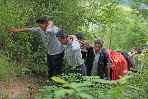 Family members carry a coffin containing the body of Zheng Shifang, 83, up a hill in Lyuting, a village in Anqing, Anhui province, on Sunday. Zheng hanged herself on May 23. New rules requiring cremation are scheduled to take effect on June 1. Chen Jie for China Daily