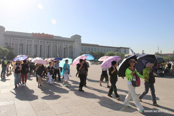 People use their sunshades to block the sun when visiting the Tian'anmen Square in Beijing, capital of China, May 28, 2014. The city's meteorological department issued this year's first yellow alert for heat Tuesday. (Xinhua/Wang Yueling)