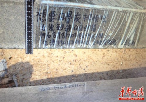 Pictured is a message left on a robbed grave that reads send your phone number to my email if you want these ashes back, along with contact information. The gravestone was partly wrapped in plastic, perhaps for fears that rain would wash away the message. Photo: voc.com.cn