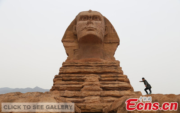 Photo taken on May 10, 2014 shows a man poses on a full-scale replica of world renowned monument the Great Sphinx of Giza constructed at the Donggou village of Shijiazhuang, Hebei province. [Photo/CFP] 