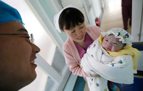 A father admires his newborn at a hospital in Qingdao, Shandong province, on Sunday. HE HAIER / FOR CHINA DAILY 