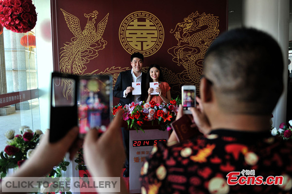 A couple poses for photos at Chaoyang district civil affairs bureau in Beijing on May 20, 2014. May 20 has an auspicious meaning since it has a similar pronunciation to "I love you" in Chinese. The day sees marriage registration boom across China every year. [Photo: Chinanews.com / Jin Shuo]