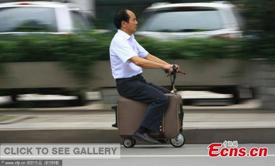 He Liangcai, a farmer from Changsha of central China's Hunan province, displays his invention "suitcase scooter" on May 28, 2014. (Photo: cfp)