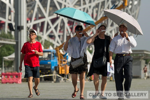 Tourists use umbrellas as a sun shade while walking at the Beijing Olympic Park in Beijing, capital of China, May 29, 2014. Temperatures in Beijing on Thursday hit a record high of around 40 degrees Celsius. (Xinhua/Luo Xiaoguang)