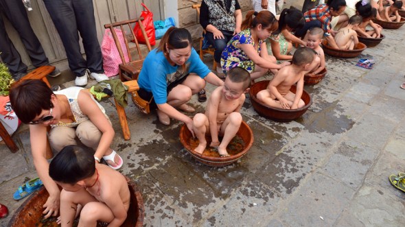 Young parents bathe their children in water with Ay Tsao to protect them from illness in Zigui, Hubei province, Qu Yuan's hometown. Zheng Jiayu / Xinhua