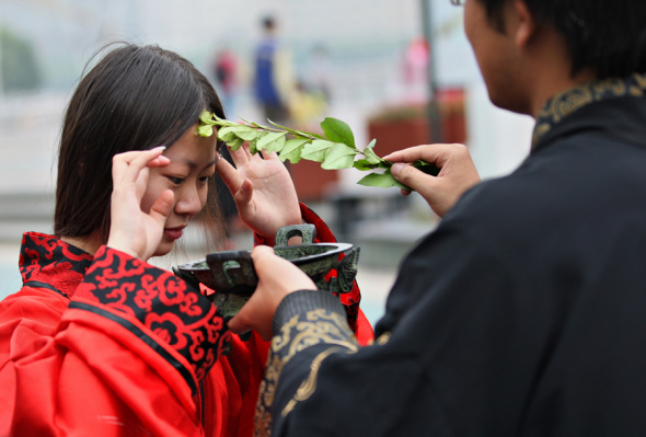 A teacher puts realgar wine on his pupil's head with Ay Tsao in a ceremony to celebrate the festival in Nantong, Jiangsu province. Xu Peiqin / Xinhua