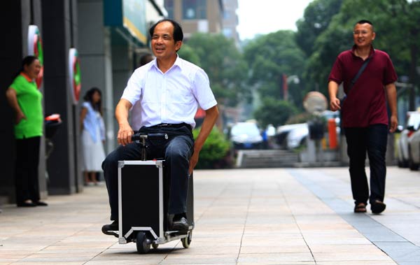 He Liangcai rides his invention - the combination of a scooter and a suitcase - in Changsha, Hunan province. The farmer has been granted a patent and expects his invention to be manufactured. Zhou Qiang / for China Daily
