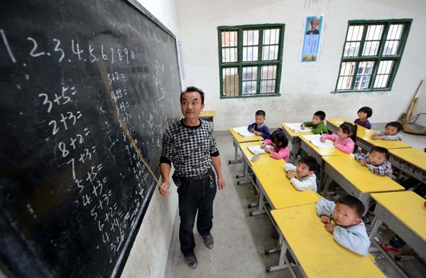 Yang Xizai, 50, the only teacher at the Lufang village school in Yihuang county in Jiangxi province, gives a math class for 14 students, including seven pre-school children, five first-graders and two second-graders. [Photo/ Xinhua]