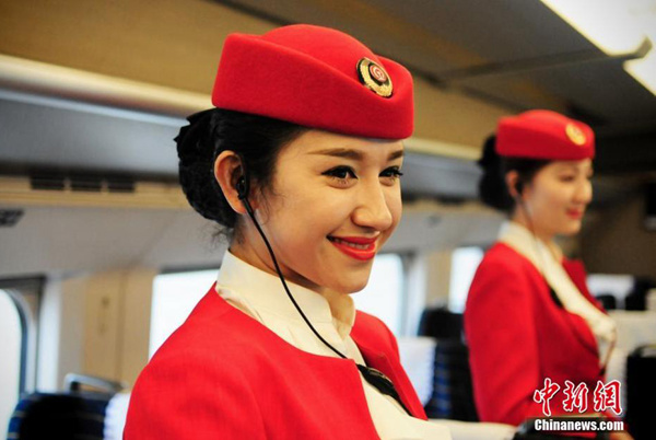 Two Uygur ethnic train conductors smile during a trial run of a high-speed train linking Northwest China's Lanzhou and Urumqi on Jun 3, 2014. [Photo by Ma Xinlong/China News Service]