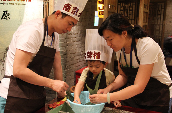 A family prepares zongzi, glutinous rice dumplings, during a family zongzi-making competition at Nanjing Impression Restaurant, which serves traditional Nanjing dishes. [Photo/chinadaily.com.cn]