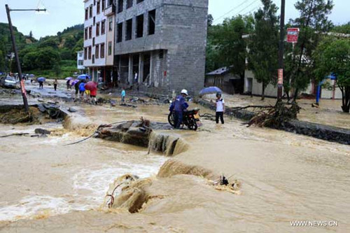 Pedestrians walk along a road damaged by flood in Baile Village under Changzhou Township in Fengshan County, south China's Guangxi Zhuang Autonomous Region, June 4, 2014.  (Xinhua/Zhou Enge)