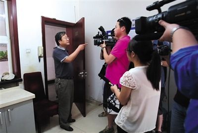 A staff member of the State Administration of Cultural Heritage asks reporters to Get out as members of the media surrounded him asking for an interview during an environmental check on its canteen cooking fumes on June 4, 2014. [Photo: The Beijing News/Gao Wei]