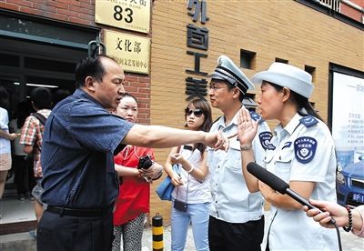 A staff member of the State Administration of Cultural Heritage talks with officials of the Beijing Municipal Environmental Monitoring Corps outside the State Administration of Cultural Heritage on June 4, 2014. [Photo: The Beijing News/Gao Wei]