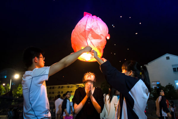 Students in Lu'an, Anhui province, release sky lanterns on Friday to pray for good luck in the national college entrance exam over the weekend. The lantern is also called Kongming lantern because the lantern was invented by Zhuge Liang, who was also named Kongming. Zhuge was known for his intelligence. [Photo/Xinhua]