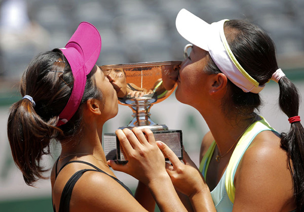 Peng Shuai of Chinese mainland (R) and Hsieh Su-Wei of Taiwan kiss the trophy during the ceremony after winning their women's doubles final match against Sara Errani and Roberta Vinci of Italy at the French Open Tennis tournament at the Roland Garros stadium in Paris June 8, 2014. [Photo/Agencies]