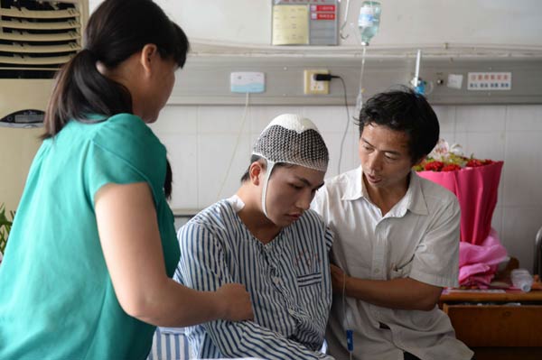 Liu Yanbing, a senior high school student in Yichun, Jiangxi province, is cared for by his parents at a local hospital ward. He was seriously injured on May 31 when he tried to fight a man who hacked bus passengers with a knife. Wu Zhonghao / Xinhua