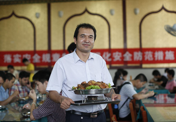 Kurbanjan Tewukel serves a chicken specialty at his halal restaurant in Wuhan University on Wednesday. Chen Zhuo / for China Daily