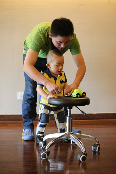 Li Shuyong plays with his son, Yuanyuan, 2, of Chongqing, on Tuesday at Beijing United Family Rehabilitation Hospital. Yuanyuan was brutally assaulted by a girl in November. He suffered brain injuries and still has trouble maintaining his balance and moving his left wrist. Wang Jing / China Daily