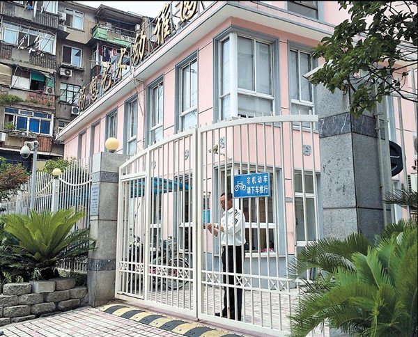 A security guard locks the gates to the kindergarten in Yangpu where a fellow worker allegedly molested three girls. — Dong Jun 