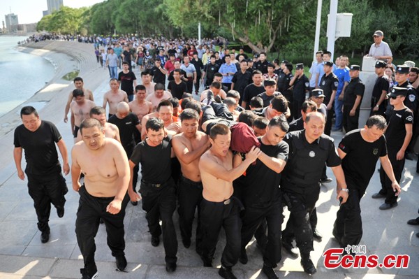 Police carry an assistant police officer in Kuerle, the Xinjiang Uygur autonomous region, June 11, 2014. [Photo/Wang Tao]