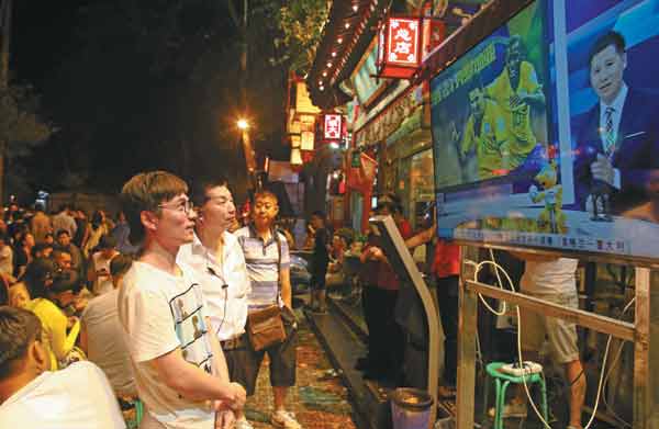 Fans watch World Cup coverage on television during an evening out in Beijing's Guijie Street on Friday. Wang Jing / China Daily 
