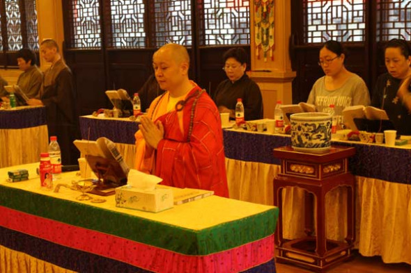 Shi Youyuan (front), head abbot of Guangde Temple, leads lay Buddhists to worship. [Photo provided to China Daily]