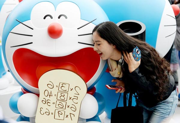 A visitor poses for a photo with a Doraemon figure at an exhibition of 100 Doraemon Secret Gadgets Expo in Beijing, capital of China, April 19, 2014. [Photo/Xinhua] 