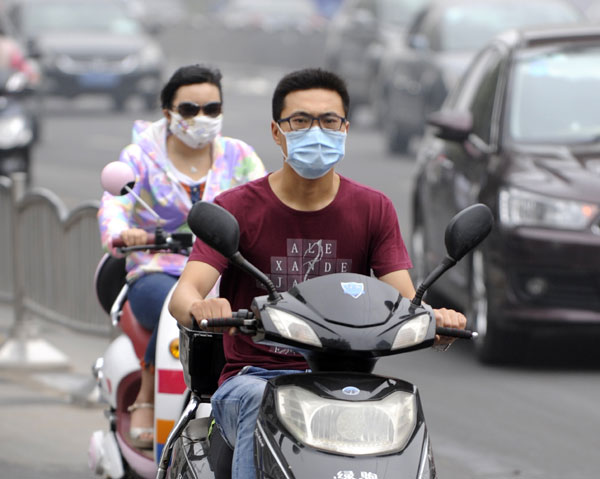 Some motorcyclists in Zhengzhou, capital of Henan province, wear masks on Wednesday for protection from the smog. The air was heavily polluted in the city. Li Bo / Xinhua