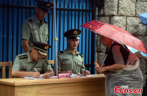 A Hong Kong citizen lines up in the rain to get her ticket to visit the military barracks of the Chinese People's Liberation Army (PLA) Garrison in Hong Kong Special Administrative Region (HKSAR) on Sunday, June 22, 2014. [Photo: China News Service/Zhang Yu]