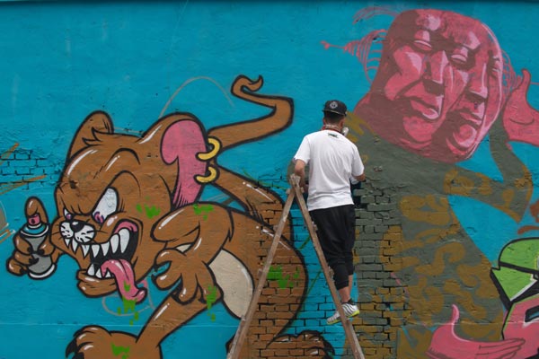 A graffiti artist works on an unfinished project on the wall of a back alley in Beijing. Wei Xiaohao / China Daily