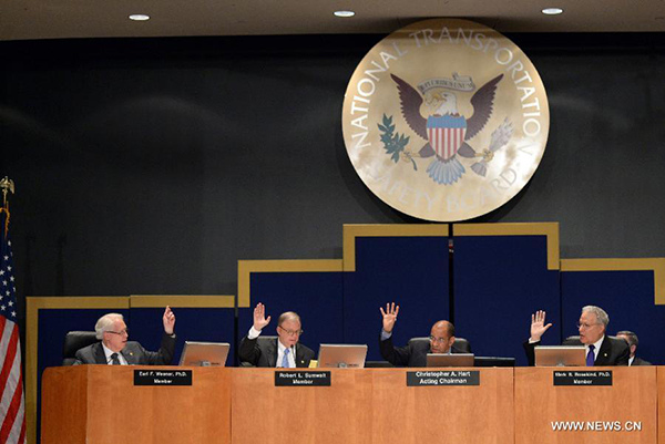 Members of National Transportation Safety Board(NTSB) raise their hands for the conclusion of the investigationon on Asiana flight accident in Washington D.C., the United States, on June 24, 2014. (Xinhua/Yin Bogu)