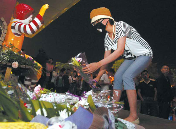 A local lays a bunch of flowers as a mark of respect for a woman murdered by alleged members of Quannengshen at a McDonald's restaurant in Zhaoyuan, Shandong province. Liu Youzhi / For China Daily