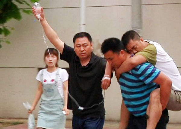 After learning of his wife's murder at a McDonald's restaurant in Zhaoyuan, her husband, seen here being carried by a friend, had to be taken to the hospital. Zhang Yulei / China News Service
