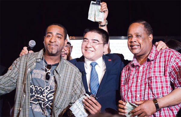 Chinese tycoon Chen Guangbiao (center) poses with men holding money as he hosts a lunch for several hundred homeless people at The Loeb Boathouse restaurant in New York City's Central Park on Wednesday. LI ANG / FOR CHINA DAILY
