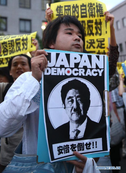 A protester holds a caricature of Japanese Prime Minister Shinzo Abe during a rally to protest against the attempt to exercise the rights to collective self-defense in front of the Prime Minister's official residence in Tokyo, Japan, June 30, 2014. (Xinhua/Liu Tian)
