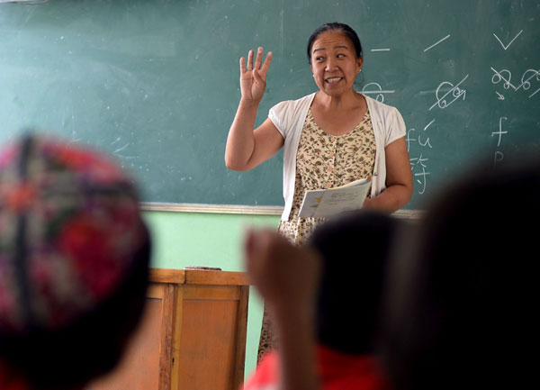 Zhou Lina, who moved in 2000 from Shenyang, Liaoning province, to Artux, Xinjiang Uygur autonomous region, with her Uygur husband Nasrula Umar, teaches a class at a primary school on Tuesday. Jin Liang / Xinhua