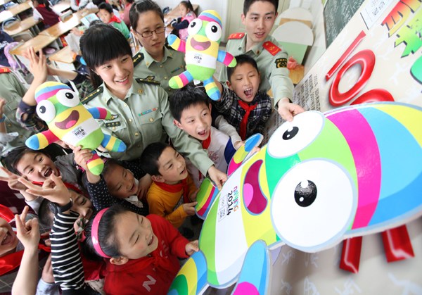 Students from Tianfeigong Elementary School make a collage of LeLe, the mascot of the 2014 Nanjing Youth Olympic Games, with guards from Nanjing Port to celebrate the 100-day countdown to the event on Thursday. Zhang Shanyu / for China Daily