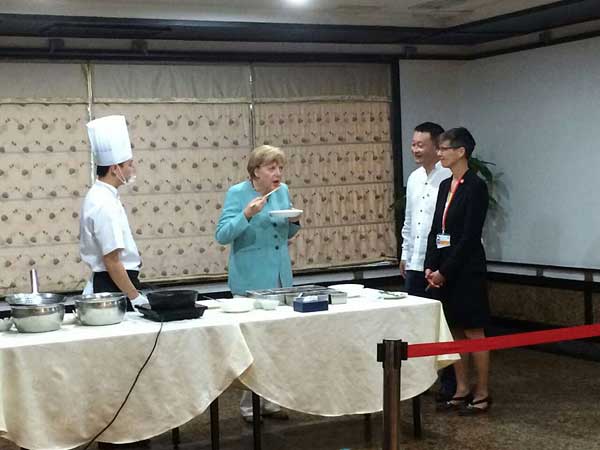 German Chancellor Angela Merkel eats kung pao chicken, a spicy Sichuan dish made with chicken, peanuts, vegetables, and chili peppers, at a Sichuan restaurant during her visit to Chengdu, the capital of Southwest China's Sichuan province, July 6, 2014. Merkel kicked off her 7th China trip Sunday in the Southwestern city, a place that German companies regard as a springboard to the relatively underdeveloped western parts of China. [Photo provided to China Daily]