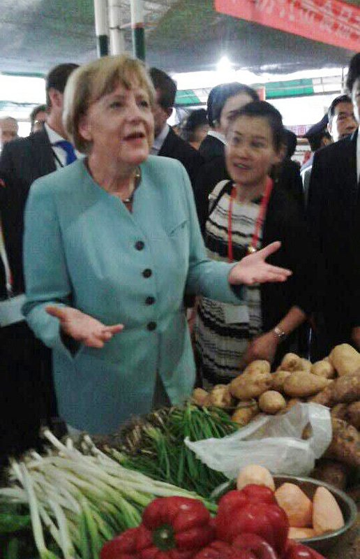 German Chancellor Angela Merkel talks to a vendor during her visit to an open market in Chengdu, the capital of Southwest China's Sichuan province, July 6, 2014. Merkel set her footprints in Chinas street life as she visited an open market and bought a bag of broad bean paste for 5 yuan ($0.8) during the visit. [Photo by Peng Chao/chinadaily.com.cn]