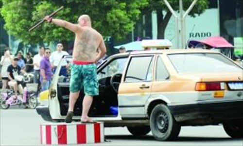 Cab driver surnamed Wang directs traffic with a stick after forcing a woman officer from her post at an intersection in Xuzhou, Jiangsu province on July 2. Photo: Modern Express