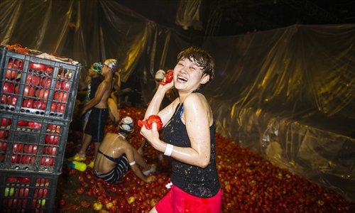 A woman prepares to hurl a tomato at Mako Livehouse in Shuangjing, Chaoyang district, on July 6. Around 50,000 tomatoes were used in a food fight at the venue involving more than 1,000 people. Photo: Li Hao/GT