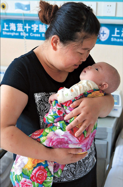 Wu Chunyan and her 2-month-old son Xi Xiazhou from Gansu Province are seen at a Shanghai hospital yesterday. Xi is being treated for spina bifida with a 100,000 yuan donation from a local woman who prefers to be anonymous. — Wang Rongjiang 