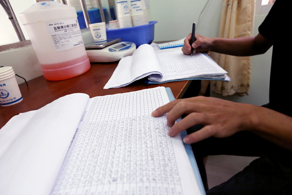A member of the medical staff calculates the amount of methadone the clinic has dispensed.[Photo by Jiang Dong / China Daily] 