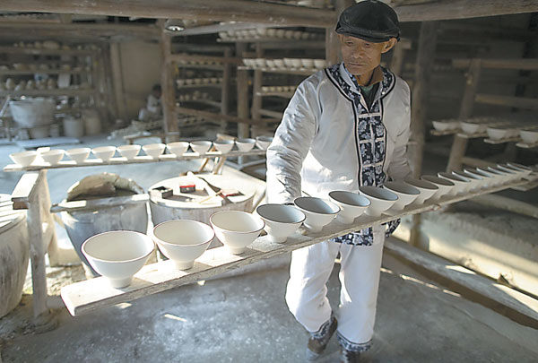 A craftsman carries half-finished porcelain at the ancient kiln museum in Jingdezhen, Jiangxi province. Photos by Zhang Hao / for China Daily