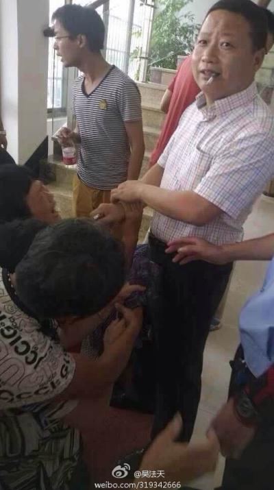 The photo shows him with a cigarette between his lips in front of the crying villagers. (Photo: screenshot from Weibo)