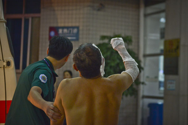 An injured man is helped by a worker at a hospital after a bus explosion in Guangzhou on Tuesday night. Zhou Wei / for China Daily