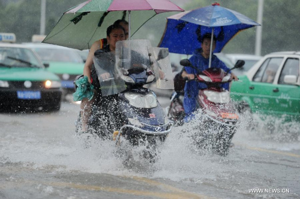 Citizens ride on a water-logged road in Guiyang, capital of southwest China's Guizhou Province, July 16, 2014. Guizhou meteorological authority on Wednesday issued a red alert for torrential rain in Guiyang where the precipitation has reached 169.5 mm. (Xinhua/Tao Liang)