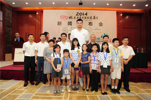 Yao Ming takes photos with officials from the China Youth Development Foundation, Chinese Basketball Association, Dongguan government and Yao Foundation, along with representatives of local children in Dongguan. Provided to China Daily